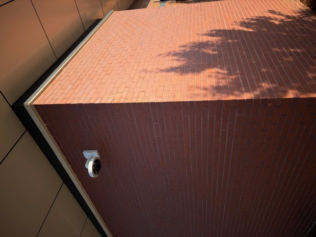 Dome camera mounted high on a brick exterior wall