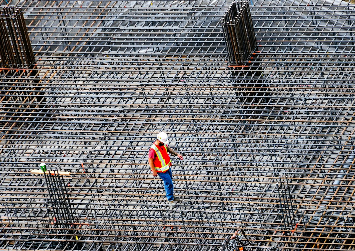 Construction worker inspecting reinforcement on a commercial building site