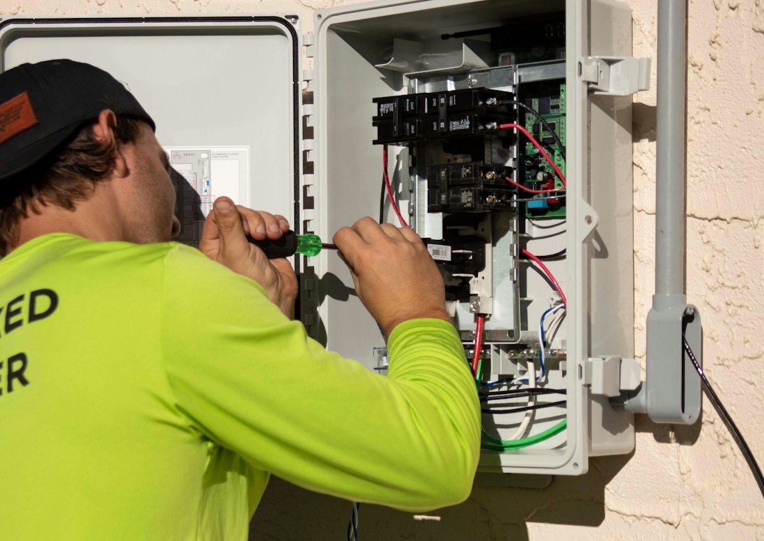 Technician working inside an electrical panel on a job site