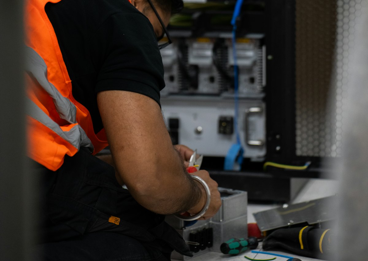 Wiscom technician servicing equipment inside a network cabinet
